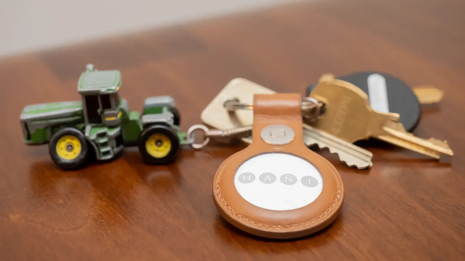 An AirTag in a leather key ring holder on a set of keys. First-generation AirTag shown; the second generation looks the same